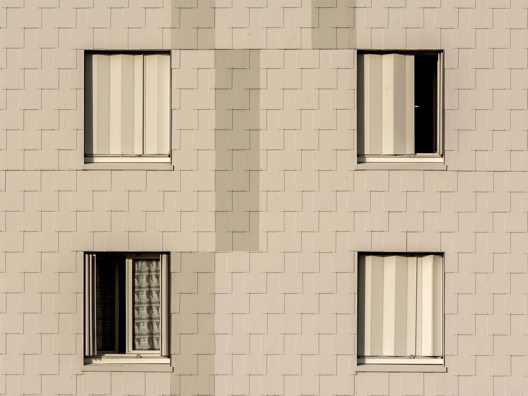 Close-up of a modern apartment building facade with symmetrical windows and beige cladding.