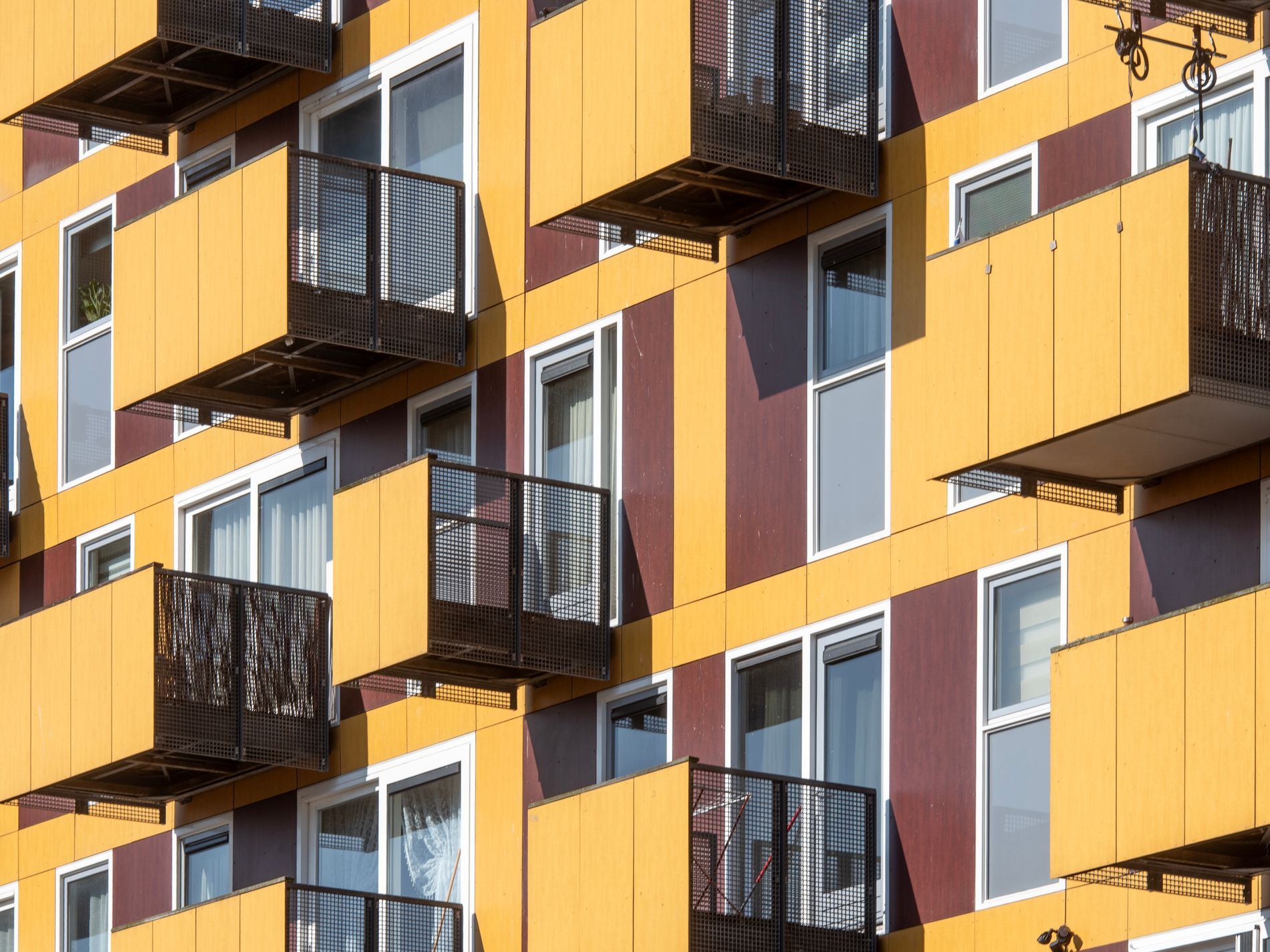 Close-up view of geometric modern residential building facade with balconies and contrasting colors.